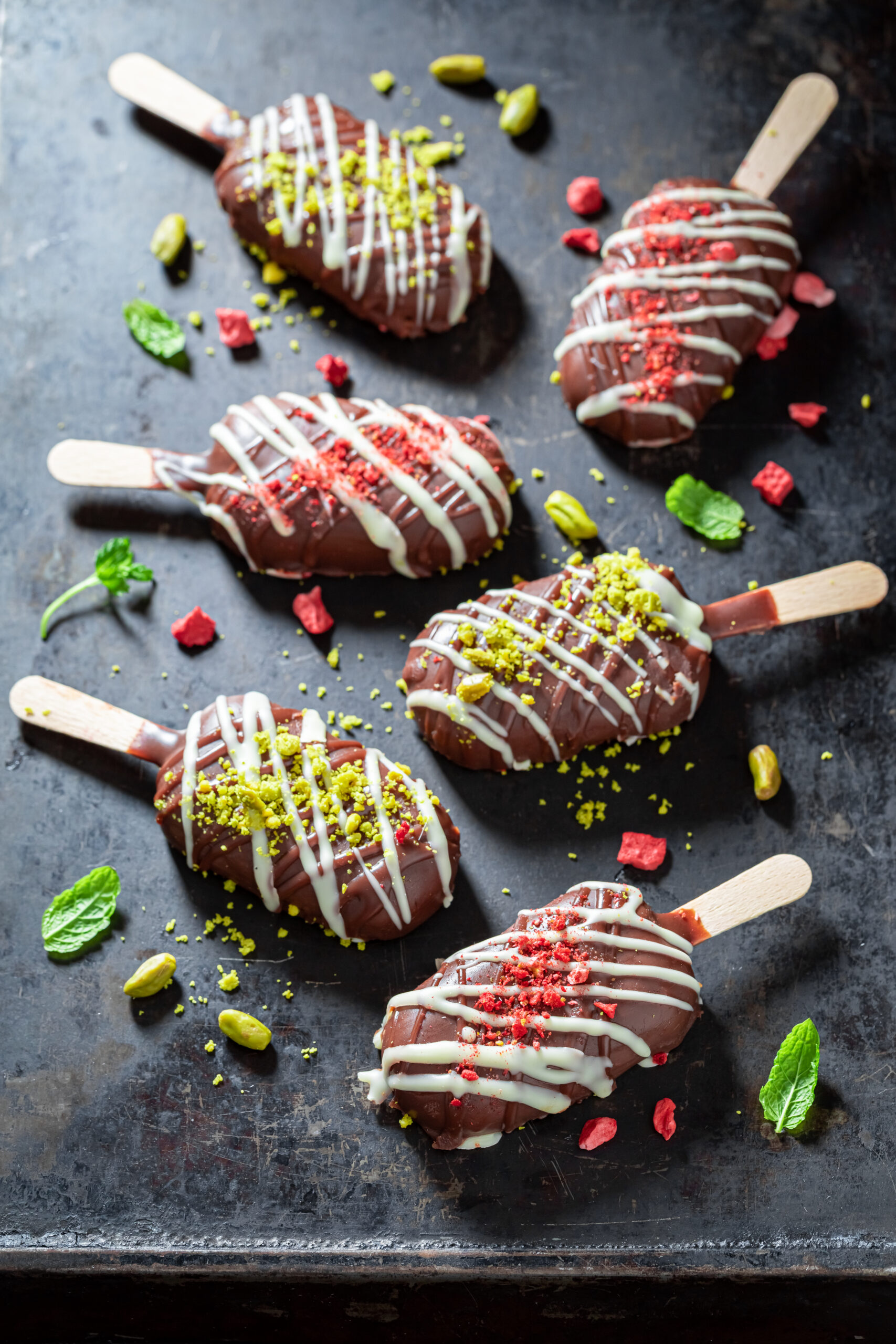 Tasty Popsicles with chocolate topping and strawberries on white baking paper